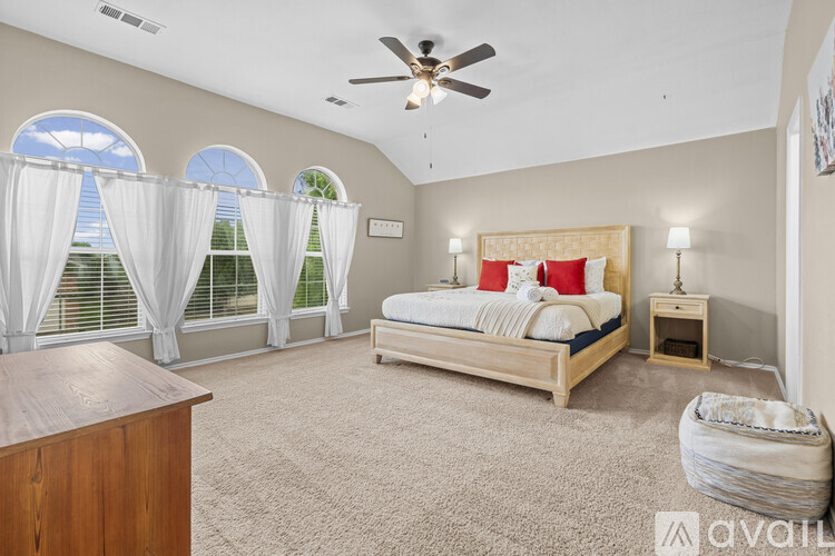 A bedroom with a large bed, a dresser, and a ceiling fan.