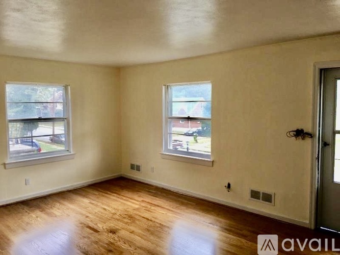 A room with wooden floors and two windows.