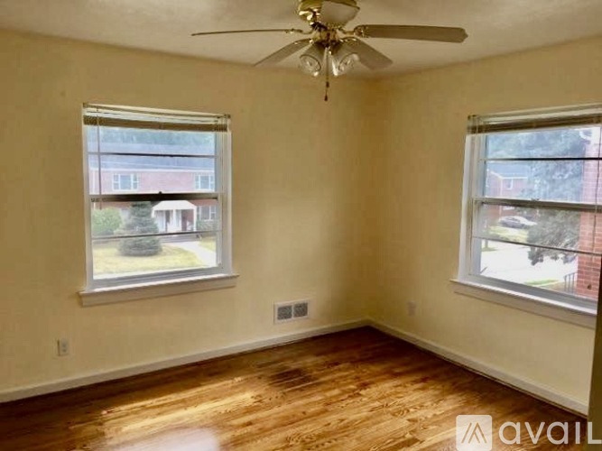 A room with a ceiling fan and two windows.