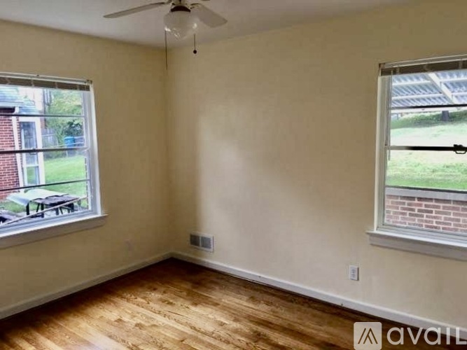 A room with a ceiling fan and two windows.