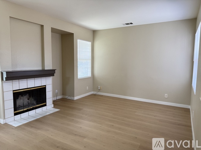 A living room with a fireplace and wooden floors.