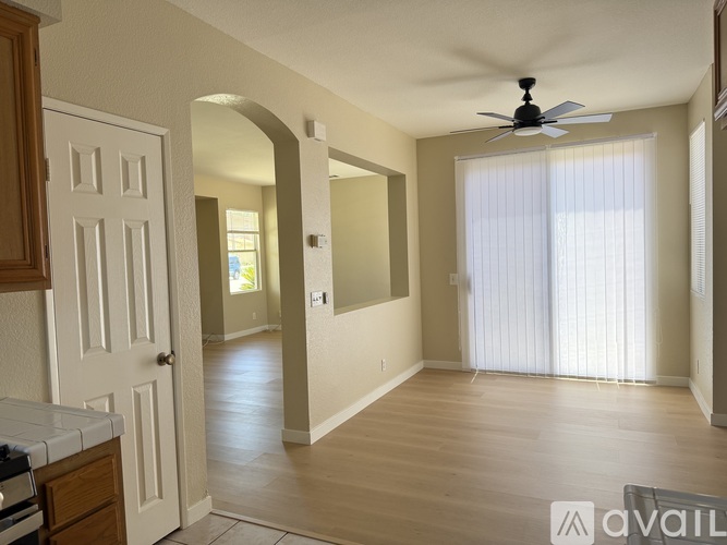 A spacious room with a fan and a door leading to another room.