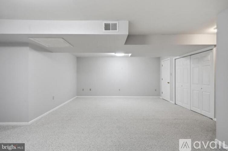 A spacious empty room with white walls and carpeted floor.