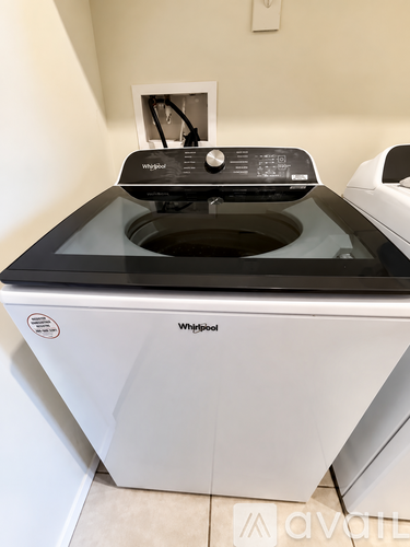 A Whirlpool washing machine with a black top and a white bottom.