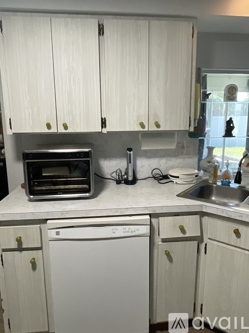 A kitchen with white cabinets and a white dishwasher.