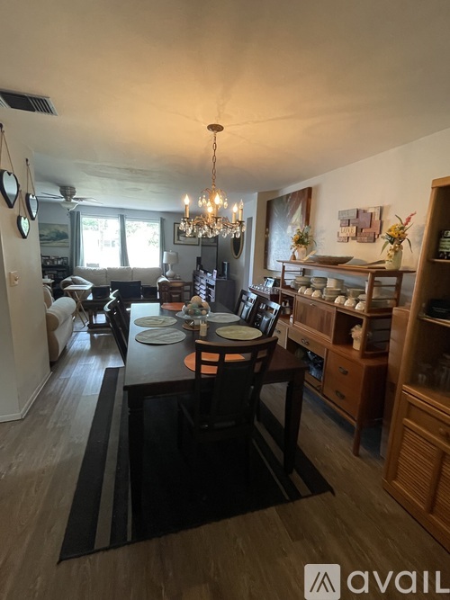 A dining room with a table set for two and a chandelier hanging from the ceiling.
