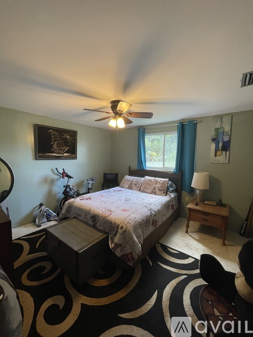 A bedroom with a bed, nightstand, and a ceiling fan.