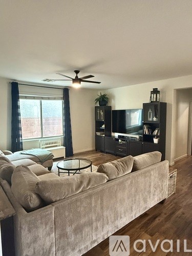 A living room with a grey couch and a ceiling fan.