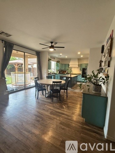 A dining room with a table set for four and a ceiling fan.