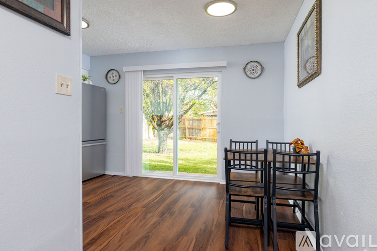 A dining room with a wooden floor and a glass door leading to a backyard.