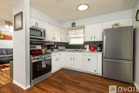 A kitchen with white cabinets and a stainless steel refrigerator.