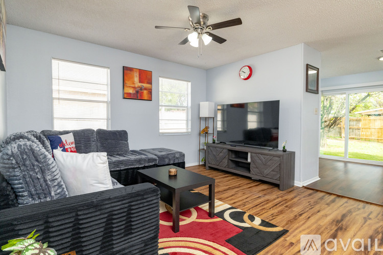 A living room with a grey couch, a black coffee table, and a red rug.