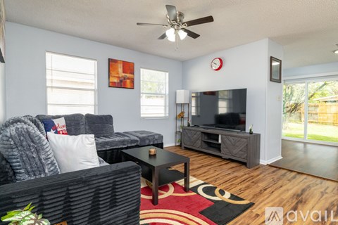 A living room with a grey couch, a black coffee table, and a red rug.