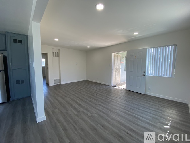 A spacious room with wooden flooring and white walls.