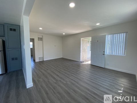 A spacious room with wooden flooring and white walls.