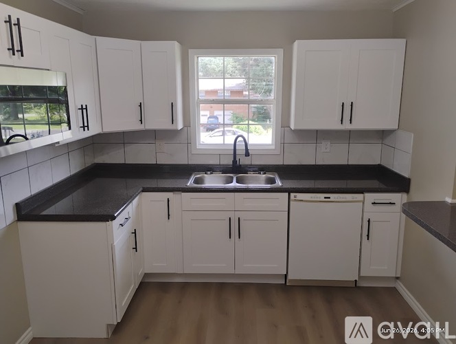 A kitchen with white cabinets and black countertops.