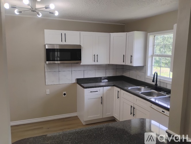 A kitchen with white cabinets and a black countertop.
