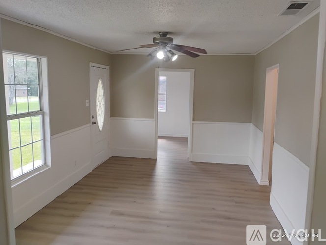 A room with a ceiling fan and wooden flooring.