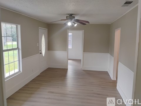 A room with a ceiling fan and wooden flooring.