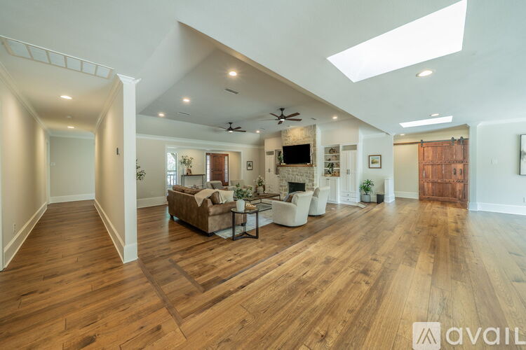 A spacious living room with hardwood floors and a skylight.