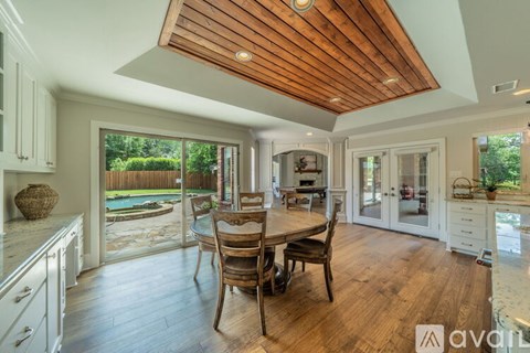 A kitchen with a wooden ceiling and a dining table with chairs.