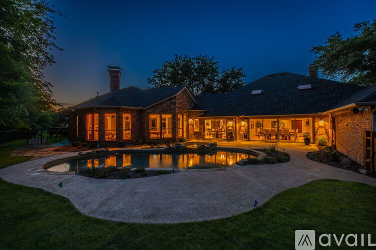 A house with a lit up pool area at night.