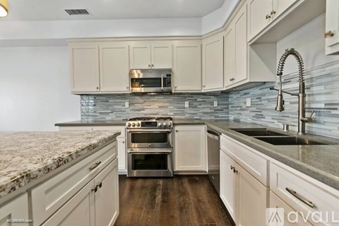 A kitchen with white cabinets and a granite countertop.
