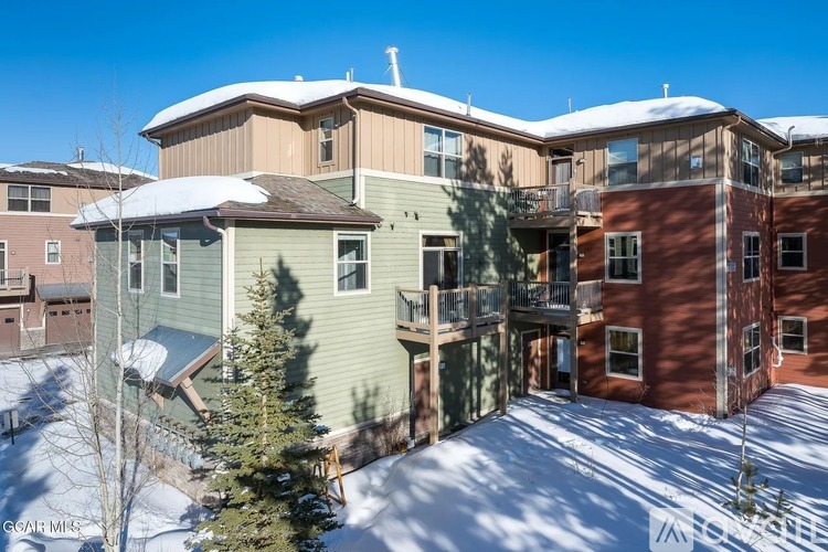 Apartment complex with snow on the ground and trees.