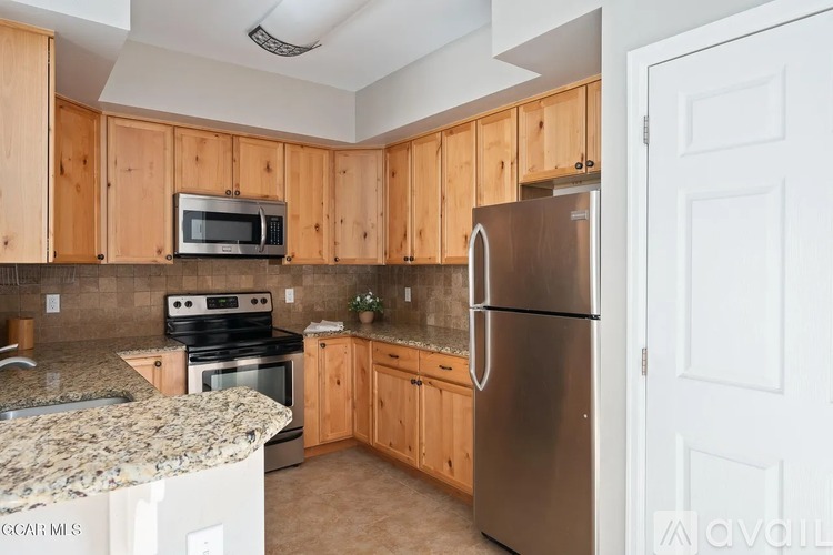 A kitchen with wooden cabinets and a stainless steel refrigerator.