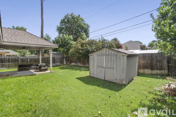 A backyard with a shed and a covered patio area.
