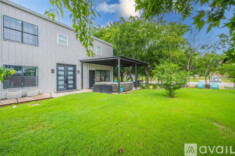A house with a green lawn and a gazebo-like structure in the yard.