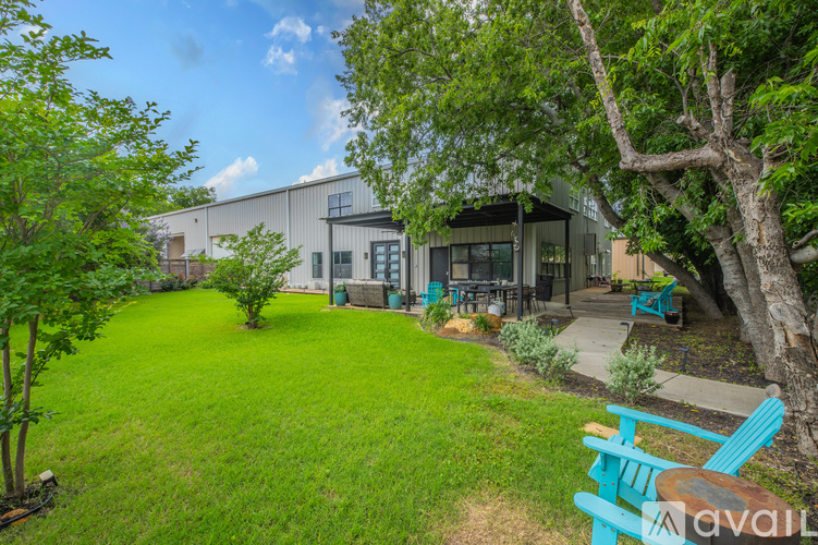 A backyard with a lawn, trees, and a blue bench.