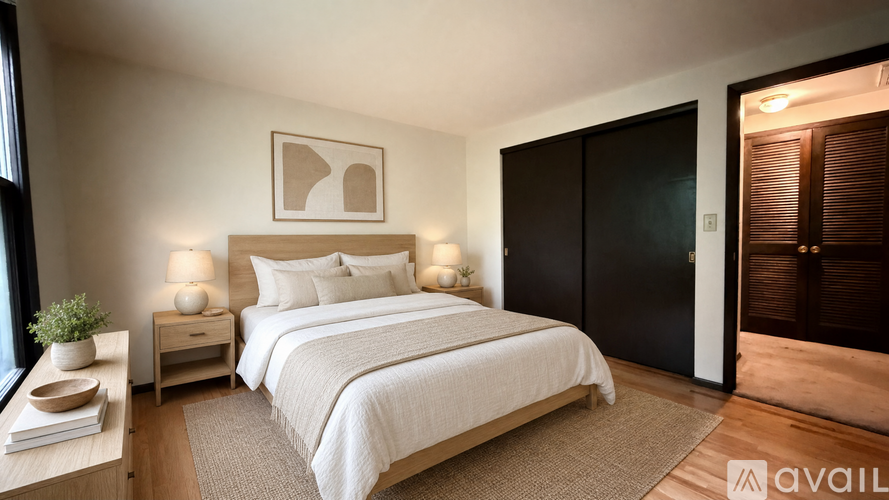 A well-lit bedroom with a large bed and a wooden floor.