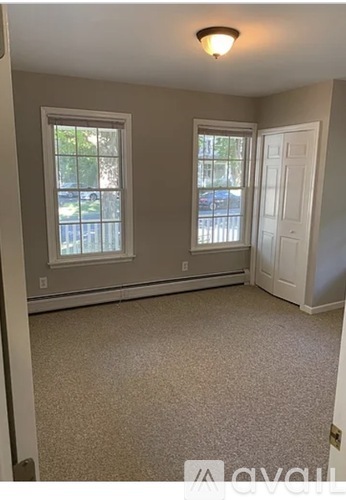 A room with a carpeted floor, two windows, and a door.