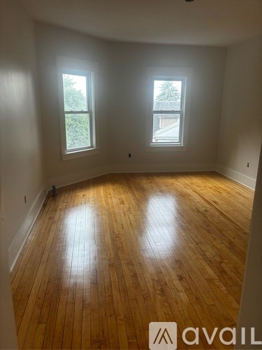 A room with wooden floors and two windows.