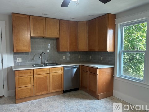 A kitchen with wooden cabinets and a window.