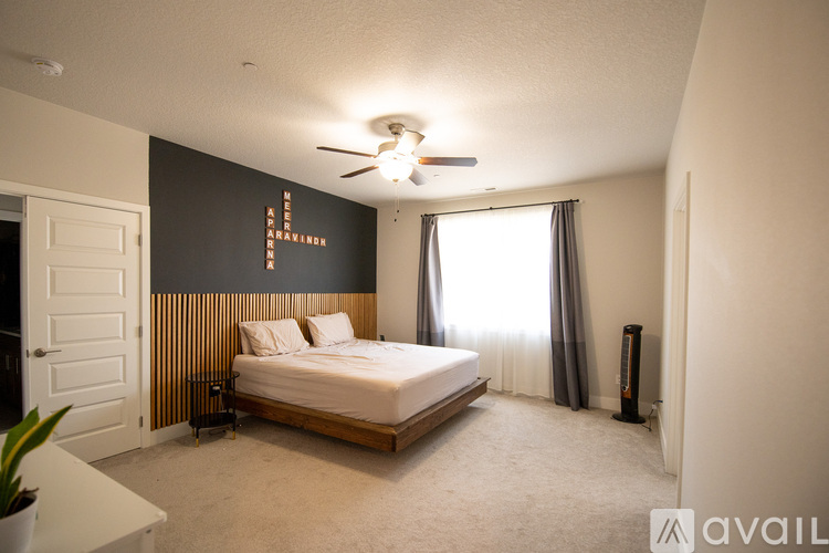 A bedroom with a bed, a ceiling fan, and a window with curtains.