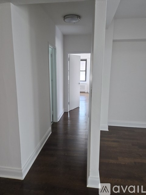 A long hallway with wood floors and white walls.