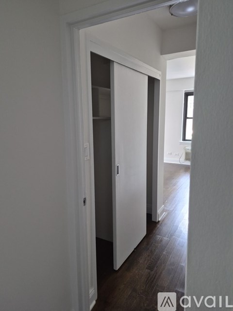 A hallway with a white door and a wooden floor.