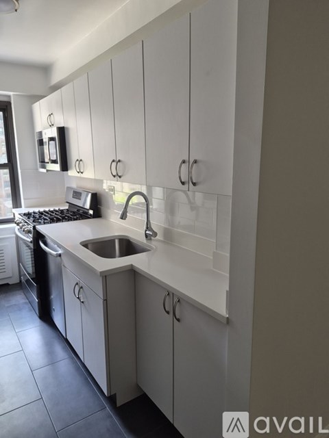 A kitchen with white cabinets and a stainless steel sink.