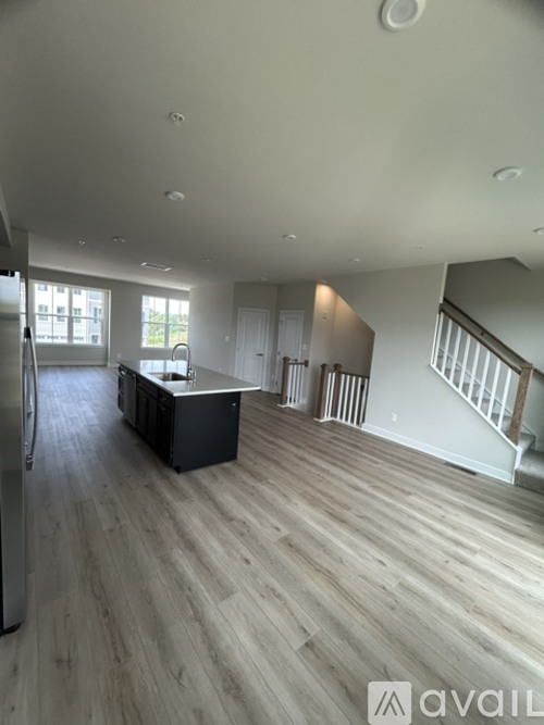 A spacious living room with wooden flooring and a staircase leading to another level.