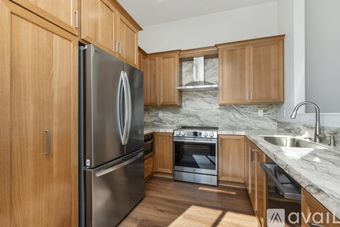 A kitchen with wooden cabinets and a marble backsplash.