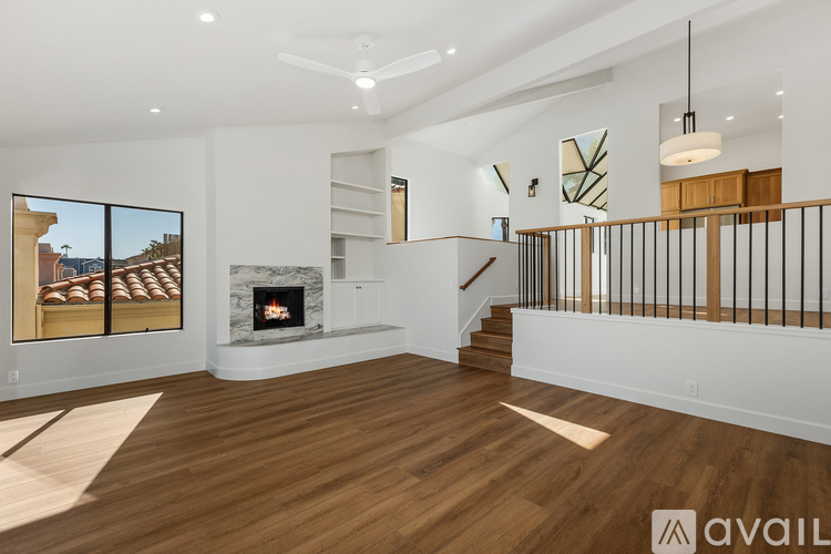 A spacious living room with a fireplace and a staircase.