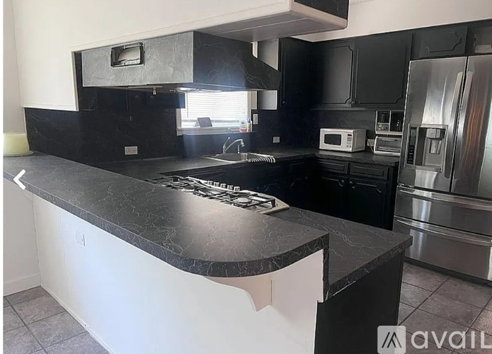 A kitchen with a black countertop and stainless steel appliances.