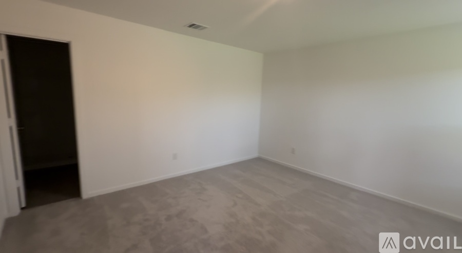 A room with a carpeted floor and a door on the left side.