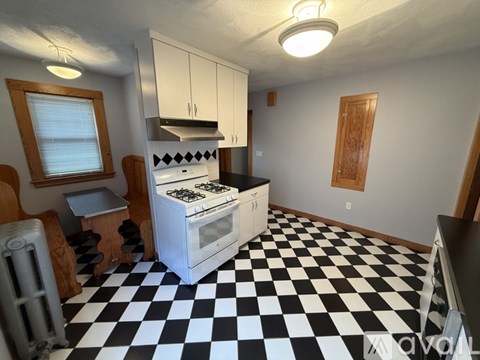A black and white checkered floor in a kitchen with a stove and cabinets.