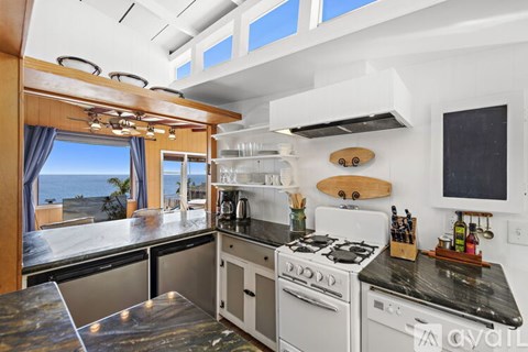A modern kitchen with a stove top oven and a window overlooking the ocean.