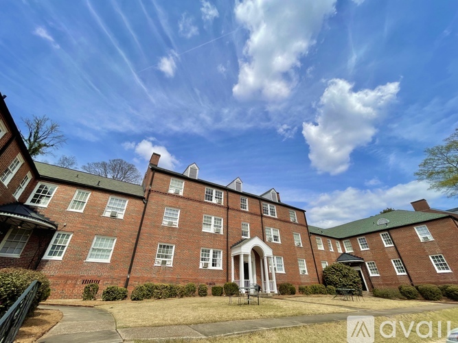 A large red brick building with a green roof and a white entrance.