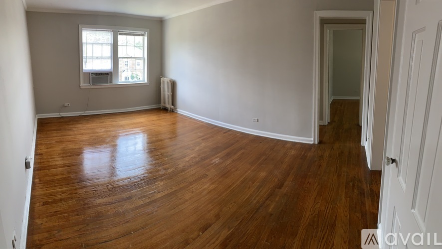 A room with wooden flooring and a window with blinds.