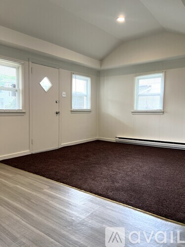 A room with a carpeted floor, a door, and a window.
